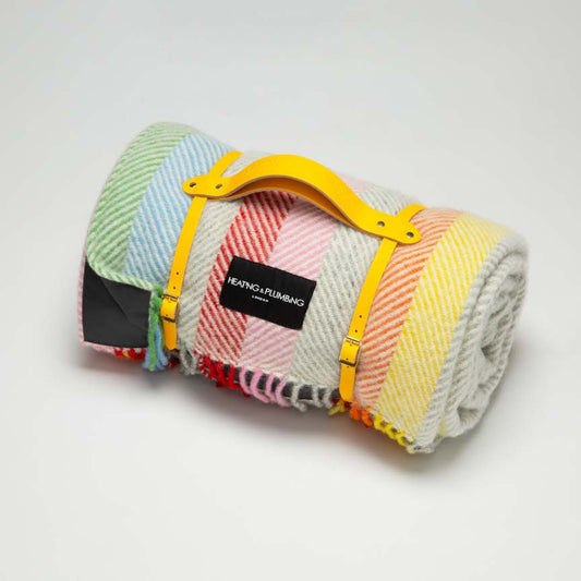 Colourful wool blanket in rainbow colours with a waterproof backing and a leather strap. Perfect for picnics.