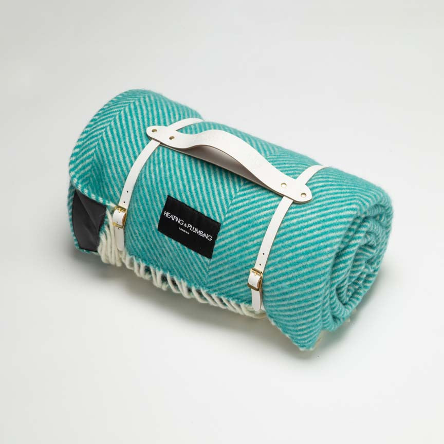 Sea blue wool blanket for picnic with white short leather strap and dark waterproof backing