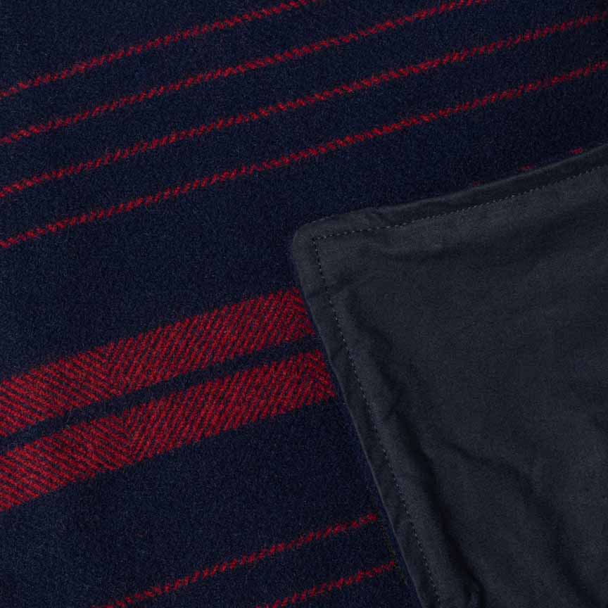 Close up product shot of marine red wool and wax picnic blanket with corner folded to show waxed backing