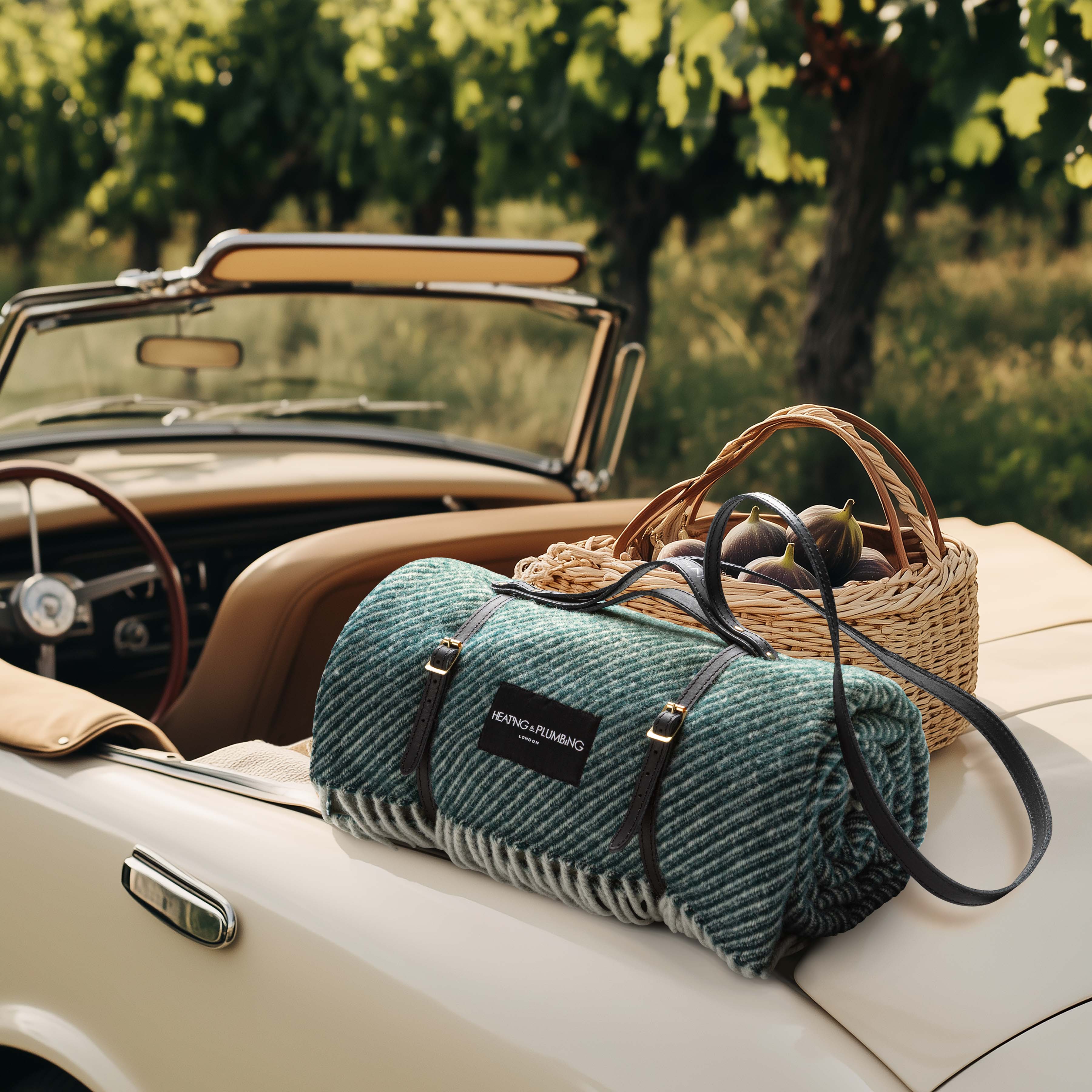 Green wool picnic blanket with black leather strap, styled on a classic convertible with wicker basket in a sunlit vineyard – digitally generated background