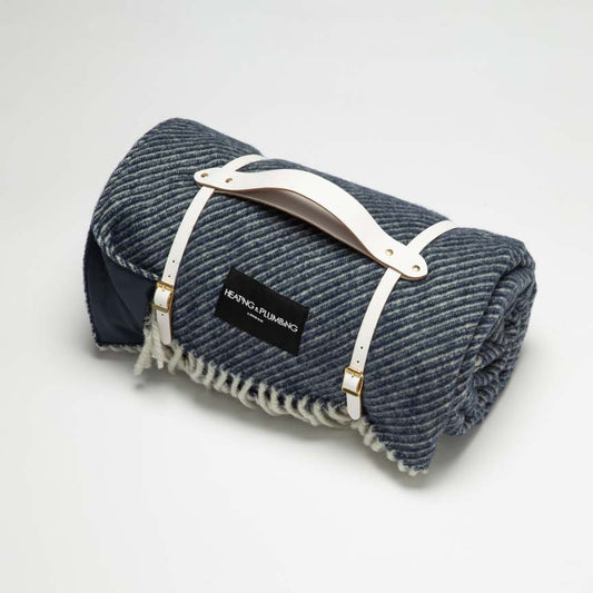 The Yacht Club is a marine blue wool picnic blanket with white strap and marine blue waterproof backing